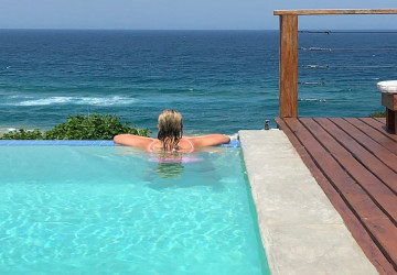 woman in negative rim flow swimming pool overlooking ocean